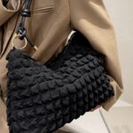 Découvrez l'exclusivité du sac à main fourre-tout noir Kate, une icône de la mode portée avec allure sur l'épaule d'une femme tendance.