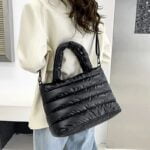 Femme portant le sac à main matelassé noir Lara en bandoulière.