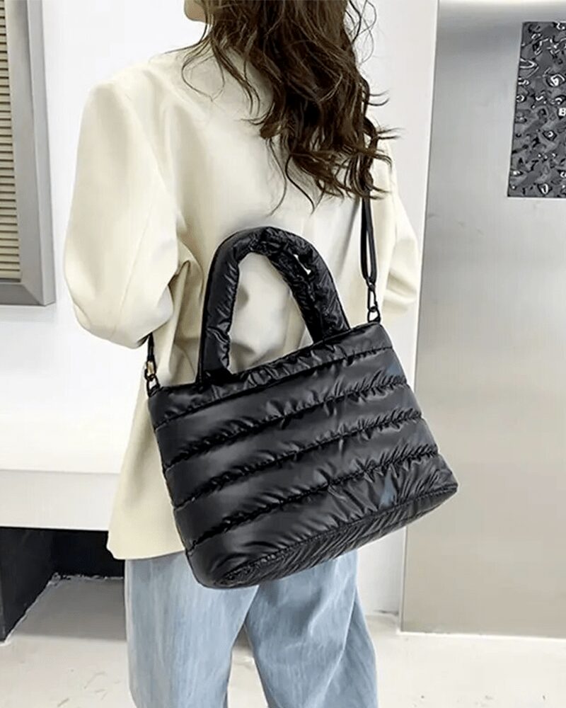Femme portant le sac à main matelassé noir Lara en bandoulière.