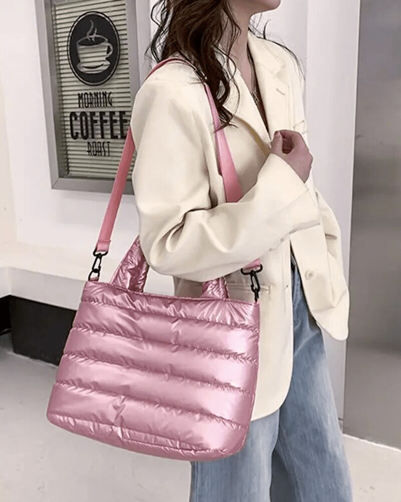 Femme portant un sac à main matelassé rose Lara sur l'épaule.