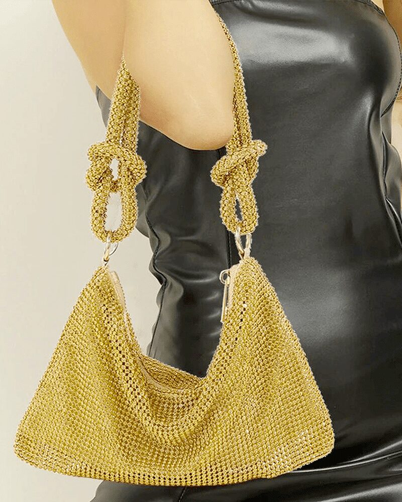 Sac à main argenté orné de strass, porté sur le bras d'une femme.