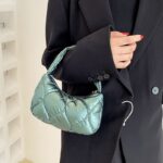Femme portant un sac à main vert Randy sur son bras.