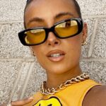 Femme portant les lunettes de soleil tendance Becky, noir et jaune, avec protection UV400.