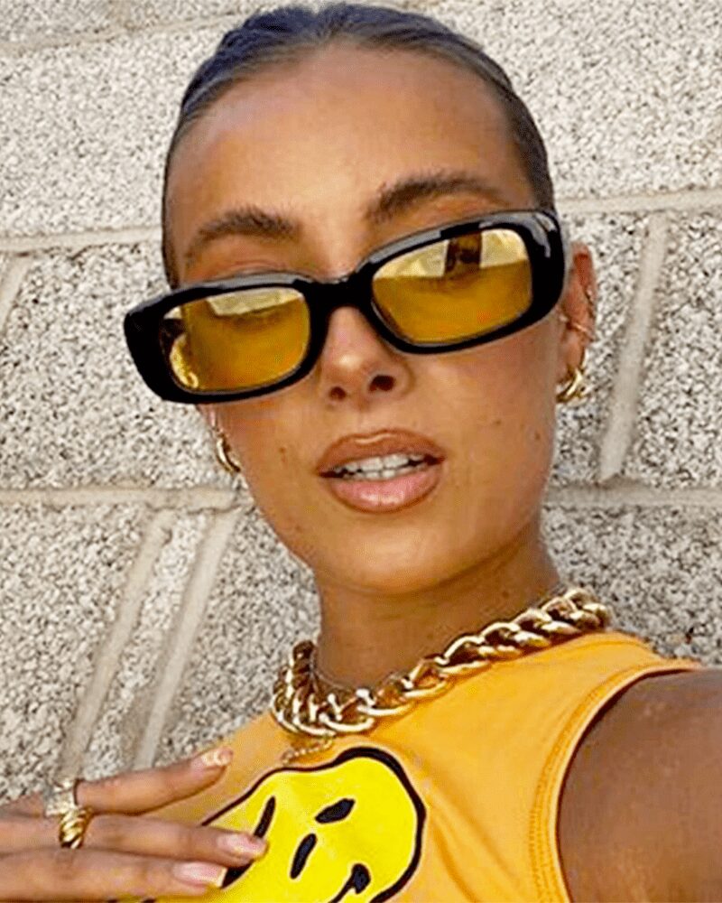Femme portant les lunettes de soleil tendance Becky, noir et jaune, avec protection UV400.