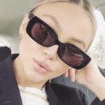 Femme portant les lunettes de soleil tendance Becky noires avec protection UV400.