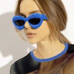 Lunettes de soleil originales Kelly bleues, offrant une protection UV400, portées par une femme.