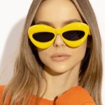 Lunettes de soleil originales Kelly jaunes, offrant une protection UV400, portées par une femme.