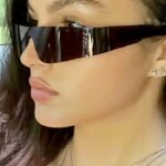 Lunettes de soleil noires Kyle, accessoire de style streetwear pour femmes avec protection UV400, portées par une femme.