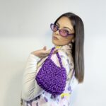 Mia sac à main violet tricoté satiné pour femme, tenu en main avec style.