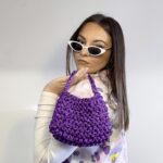 Mia sac à main violet tricoté satiné pour femme, tenu en main.