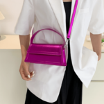 Femme portant un sac à main rose en similicuir brillant avec bandoulière.