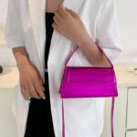 Sac à main Nawel rose en similicuir brillant - accessoire chic pour femme porté au bras.