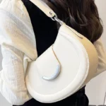 Sac à main Anaïs en similicuir blanc porté à l'épaule par une femme, disponible chez Boutique Izamel.