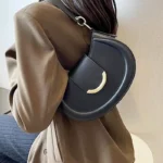Sac à main Anaïs en similicuir noir porté à l'épaule par une femme, disponible chez Boutique Izamel.