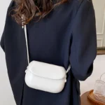 Sac à main Emy en similicuir blanc avec bandoulière porté par une femme, disponible chez Boutique Izamel.