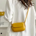 Sac à main Emy en similicuir jaune avec bandoulière porté par une femme, disponible chez Boutique Izamel.