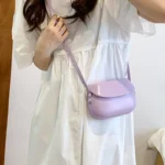 Sac à main Emy en similicuir lila avec bandoulière porté par une femme, disponible chez Boutique Izamel.