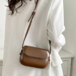 Sac à main Emy en similicuir marron porté à l'épaule par une femme, disponible chez Boutique Izamel.