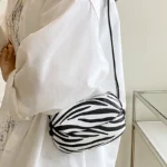 Sac à main Emy en similicuir avec motif zébré, porté à l'épaule par une femme, disponible chez Boutique Izamel.