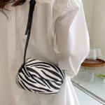 Sac à main Emy en similicuir avec motif zébré, porté à l'épaule par une femme, disponible chez Boutique Izamel.