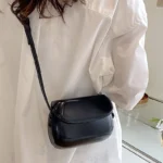 Sac à main Emy en similicuir noir avec bandoulière porté par une femme, disponible chez Boutique Izamel.