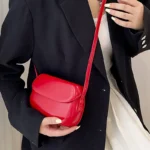 Sac à main Emy en similicuir rouge avec bandoulière, porté par une femme, disponible chez Boutique Izamel.