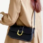 Sac à bandoulière noir vernis Inaya porté par une femme