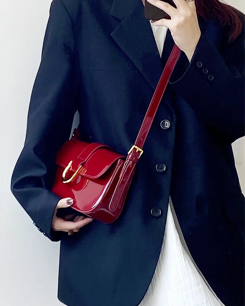 Sac à bandoulière rouge vernis Inaya porté par une femme
