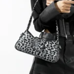 Sac à main Iris avec motif léopard blanc porté au bras par une femme, disponible chez Boutique Izamel.
