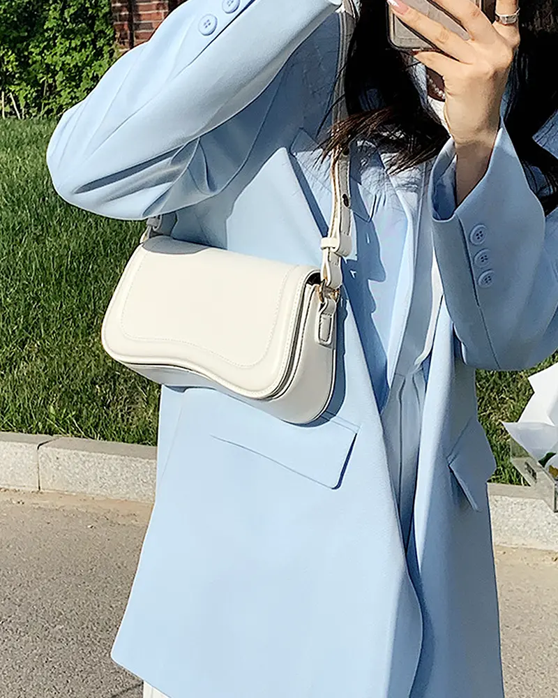 Sac à main Lina en similicuir blanc porté à l'épaule par une femme, disponible chez Boutique Izamel.