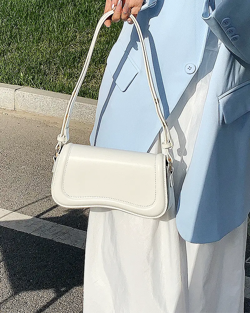 Sac à main Lina en similicuir blanc tenu à la main par une femme, disponible chez Boutique Izamel.