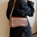 Sac à main Lina en similicuir marron porté à l'épaule par une femme, disponible chez Boutique Izamel.