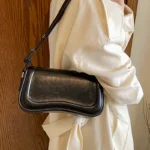 Sac à main Lina en similicuir noir porté à l'épaule par une femme, disponible chez Boutique Izamel.