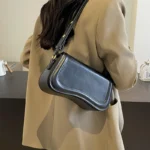 Sac à main Lina en similicuir noir porté à l'épaule par une femme, disponible chez Boutique Izamel.