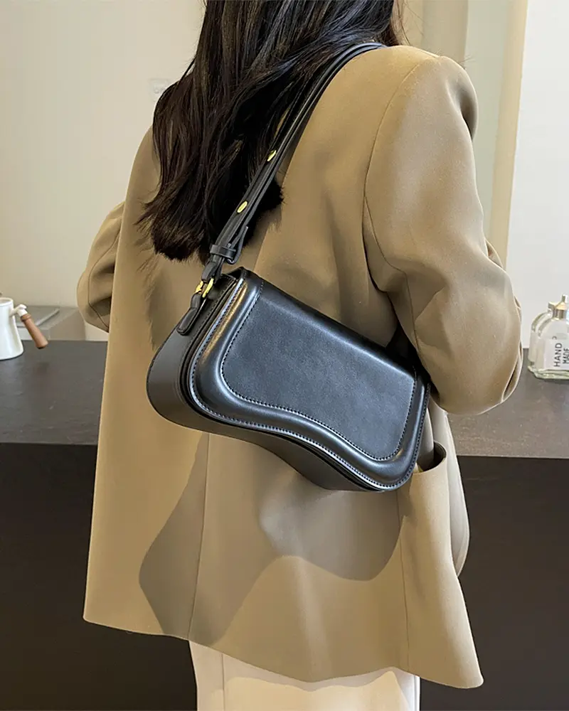 Sac à main Lina en similicuir noir porté à l'épaule par une femme, disponible chez Boutique Izamel.