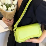 Sac à main Lina en similicuir vert porté à l'épaule par une femme, disponible chez Boutique Izamel.