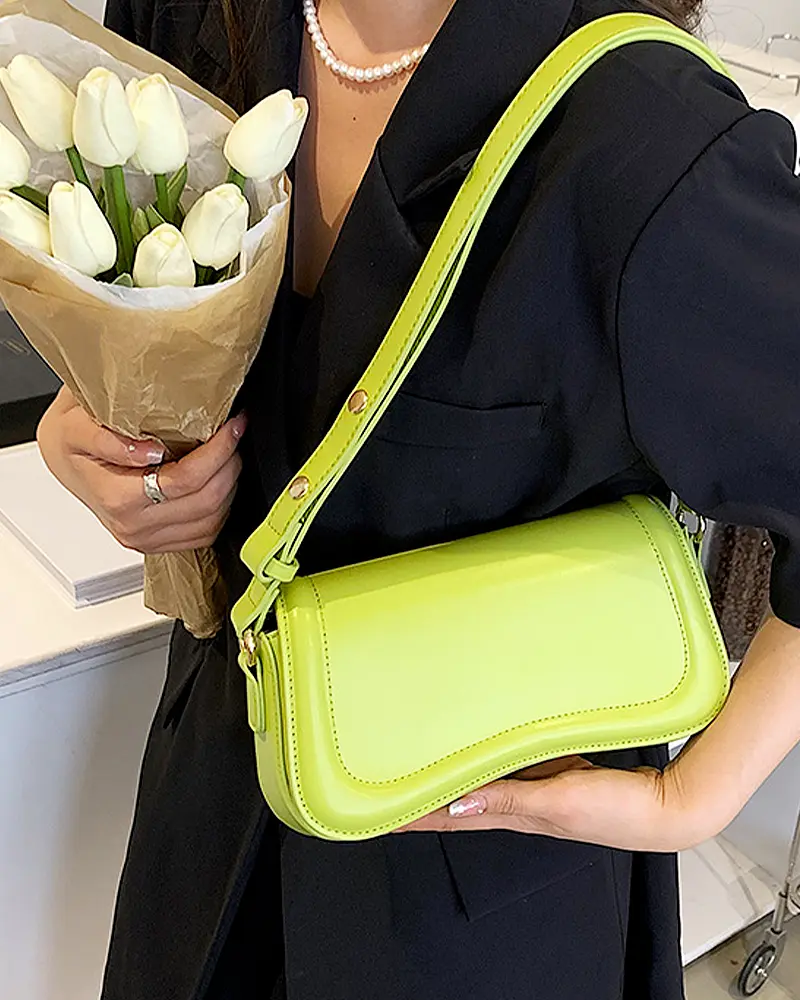 Sac à main Lina en similicuir vert porté à l'épaule par une femme, disponible chez Boutique Izamel.
