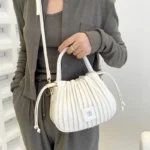 Sac à main Mia plissé blanc porté en bandoulière par une femme, disponible chez Boutique Izamel.