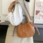 Sac à main Mia plissé caramel porté à l'épaule par une femme, disponible chez Boutique Izamel.