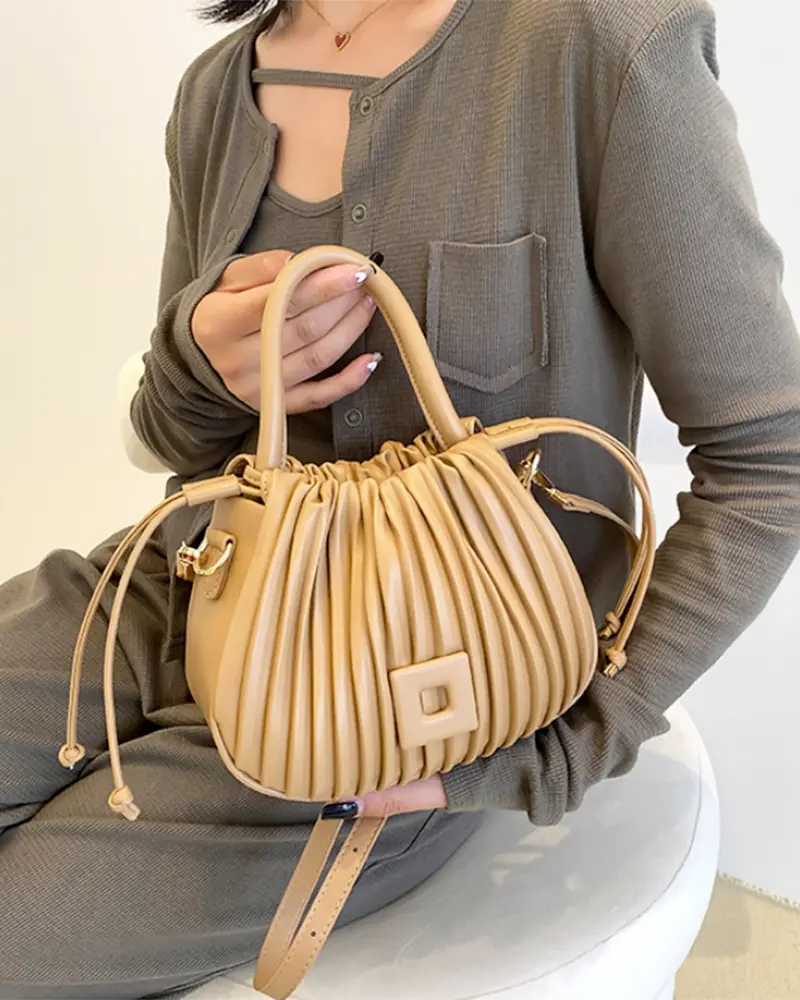 Sac à main Mia plissé crème tenu à la main par une femme, disponible chez Boutique Izamel.