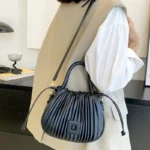 Sac à main Mia plissé noir porté à l'épaule par une femme, disponible chez Boutique Izamel.