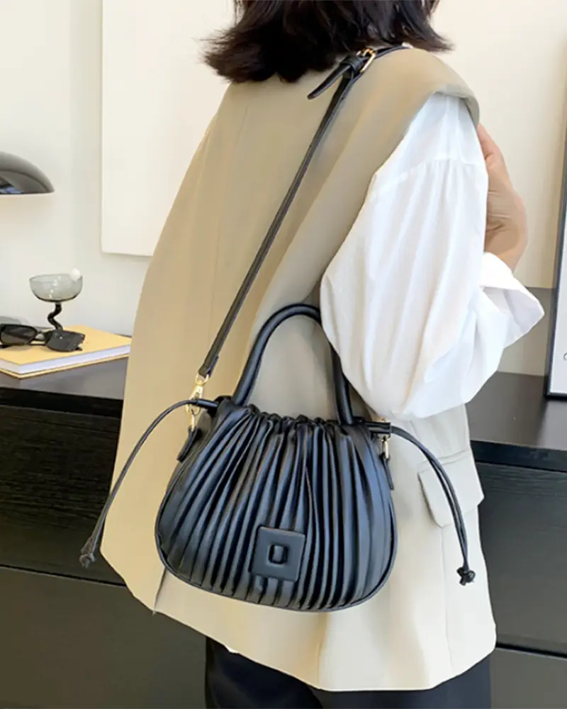 Sac à main Mia plissé noir porté à l'épaule par une femme, disponible chez Boutique Izamel.