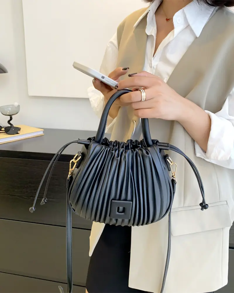 Sac à main Mia plissé noir tenu à la main par une femme, disponible chez Boutique Izamel.