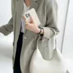 Sac à main Samia en similicuir blanc porté au bras par une femme, disponible chez Boutique Izamel.