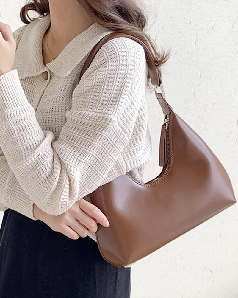 Sac à main Samia en similicuir marron porté à l'épaule par une femme, disponible chez Boutique Izamel.
