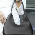 Sac à main Samia en similicuir noir tenu à la main par une femme, disponible chez Boutique Izamel.