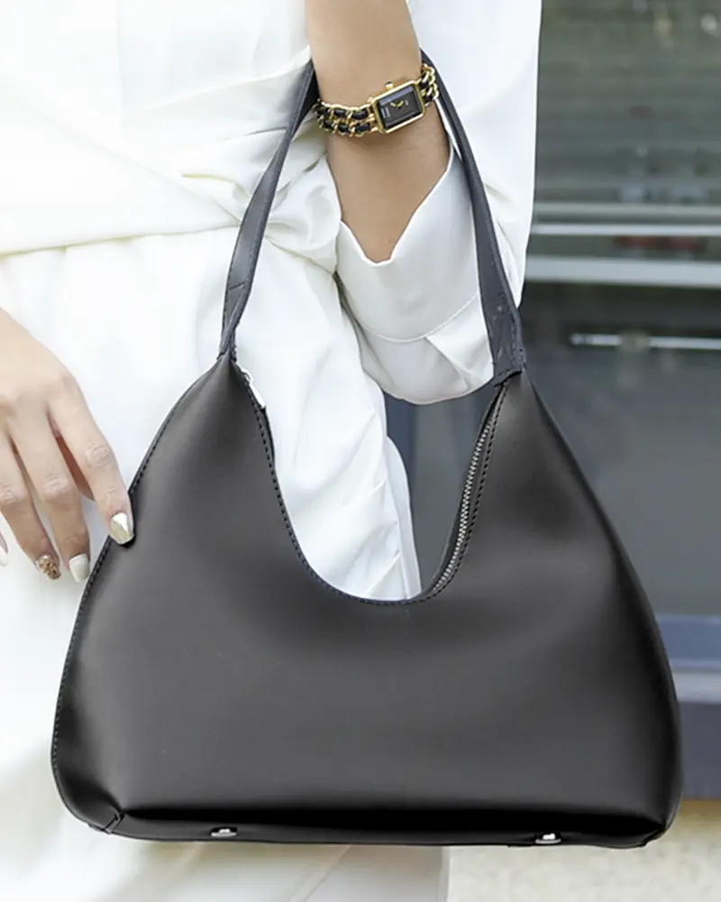 Sac à main Samia en similicuir noir tenu à la main par une femme, disponible chez Boutique Izamel.